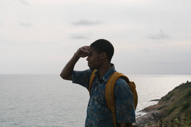 Man shielding her eyes from sun shine looking out over coastlinre