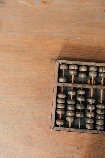 A wooden antique abacus lays flat on top of a wooden table, instrument used for counting