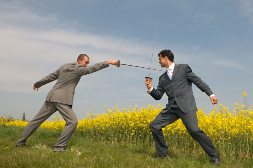 Businessmen sword fighting