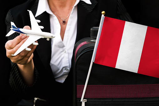 business woman holds toy plane travel bag and flag of Peru .