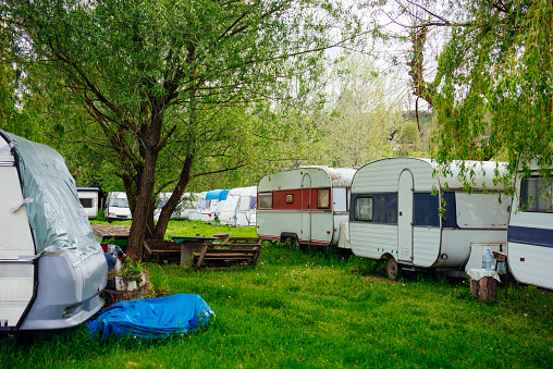 Caravan trailer on a green lawn in a camping site. Sunny day. Spring landscape. Europe. Lifestyle, travel, ecotourism, road trip, journey, vacations, recreation, transportation, RV, motorhome.