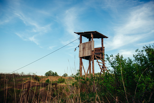 Old wooden fire protection watchtower on top of the hill. A guard tower for a temporary camp or for searching for fires. The concept of control and monitoring of people and their actions.