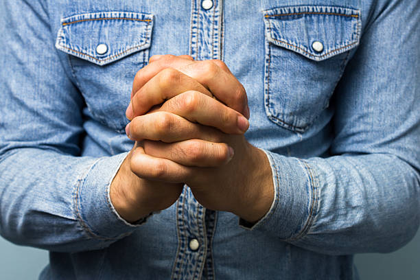Blue collar worker with hands folded Close up on the hands of a man in stereotypical working class shirt as he is praying. signs and symbols stock pictures, royalty-free photos & images