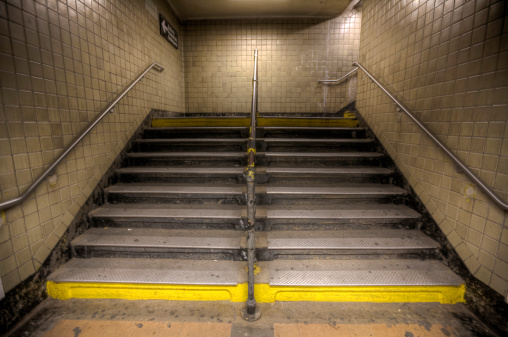 An upward view of a HDR photo of a NYC Subway staircase.