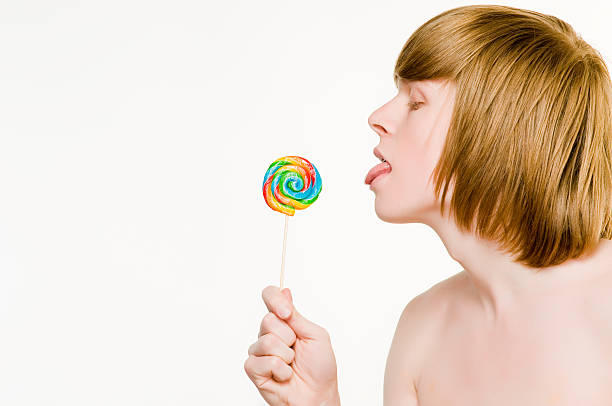 Young red-haired man licking lollipop stock photo