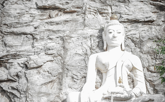 The Buddha image is carved from a cliff and a stone wall with the belief and faith of Buddhist craftsmen in Thailand.