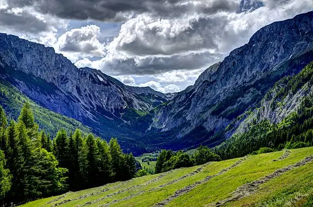 A beautiful HDR landscape image of an alpine valley in Austria in the summertime with a meadow in the foreground.