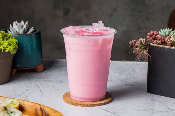 iced strawberry milk or rose milk served in disposable glass with ice cube isolated on wooden board side view of taiwanese ice drink iced strawberry milkshake or rose milk served in disposable glass with ice cube isolated on wooden board side view of taiwanese ice drink pink tea stock pictures, royalty-free photos & images