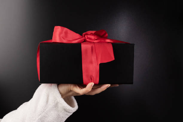 istock luxury gift, Hand with a black present box, Valentine's surprise, ribbon wrap, romantic event 1790688331