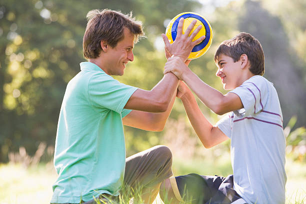 istock Man and young boy outdoors holding soccer ball, smiling 179070216
