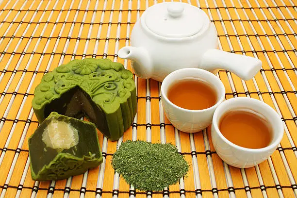 Greentea mooncake slice into quarter put together with teacup and teapot.