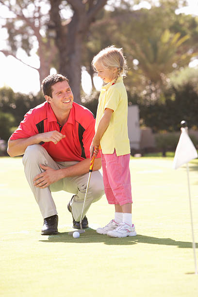 père et sa fille d'enseignement à jouer au golf sur notre putting green - putting down photos et images de collection