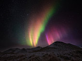 Colorful Aurora Borealis above snowcapped mountains during the ngiht in Iceland.