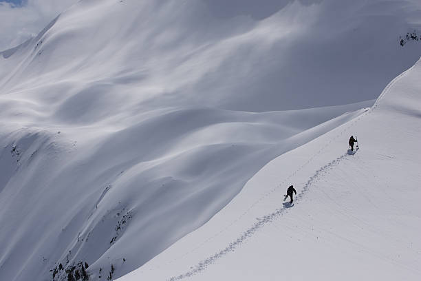 Snowboarders Hike a backcountry ridge 1 stock photo