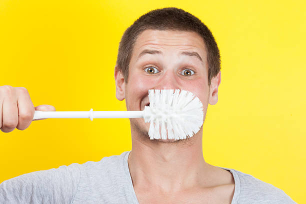 Brushing teeth Young man brushing teeth with toilet brush toilet brush stock pictures, royalty-free photos & images