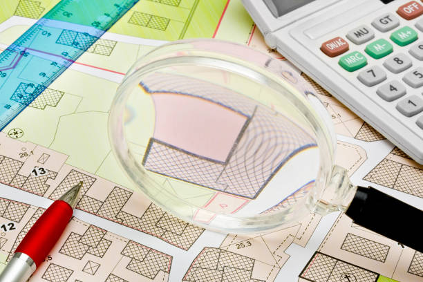 Imaginary cadastral map with buildings, land parcel and vacant plot - property registry and real estate concept seen through a magnifying glass - note: the map background is totally invented and does not represent any real place stock photo