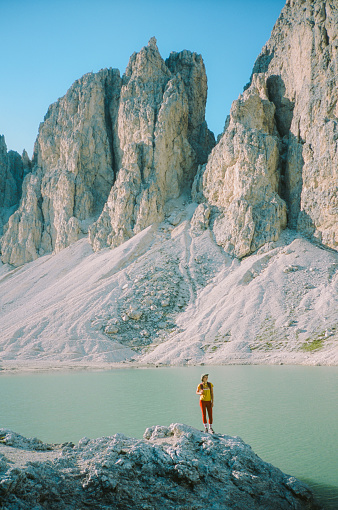 Woman hiking near lake Antermoia in Dolomites in summer. Shot on camera film