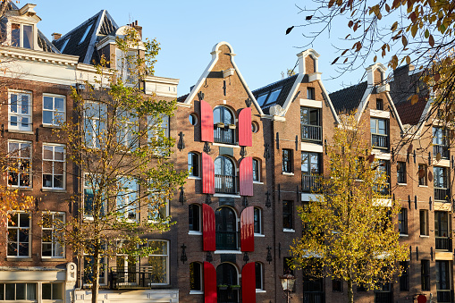 Canal house with red wooden window shutters in Amsterdam, The Netherlands.