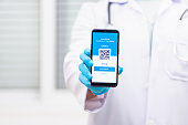 Doctor man in medical mask show app smartphone mobile digital vaccinated passport coronavirus