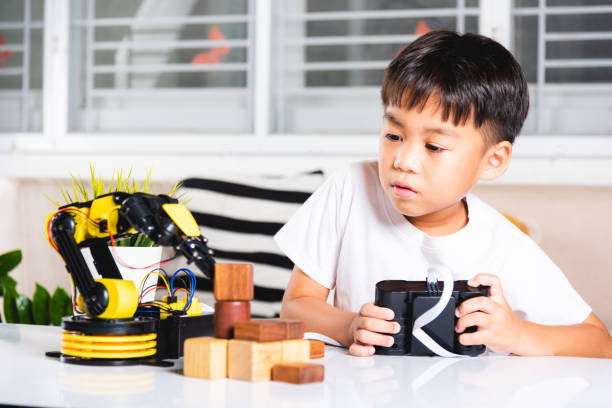istock Happy Asian little kid boy using remote control playing robotic machine arm for pick up wood block 1790761908