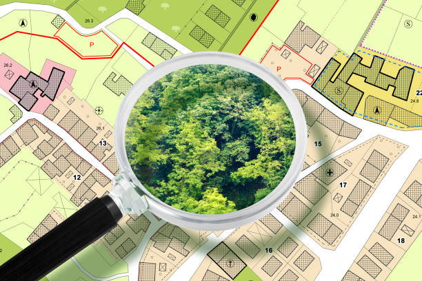 istock Imaginary Cadastral and General Urban Planning with buildings, land parcel and vacant plot - land records and property registry concept with woodland seen by a magnifying glass 1790766658