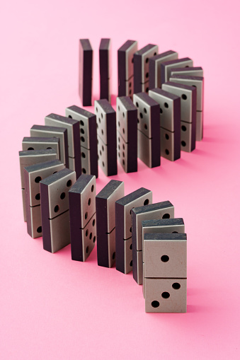 Row of domino tiles on pink studio background close up