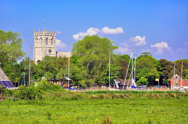 Christchurch Priory Christchurch Priory taken from Stanpit Marshes on a sunny day showing the masts of boats on the river. christchurch england photos stock pictures, royalty-free photos & images
