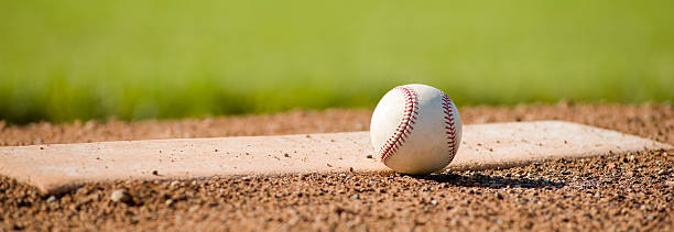 A baseball on a white mound on a field stock photo
