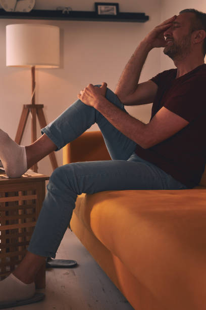 istock Man with knee pain sitting on a sofa at home. 1790789690