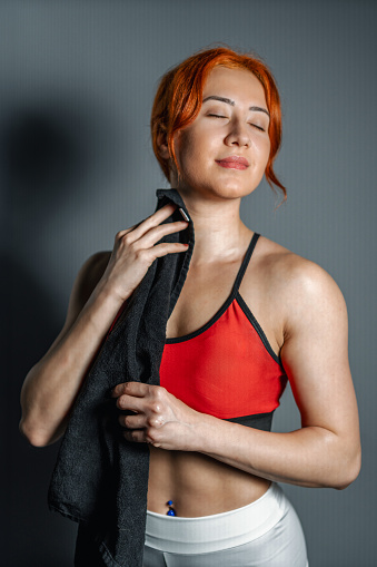 Strong and muscular woman is drying her sweat with a towel