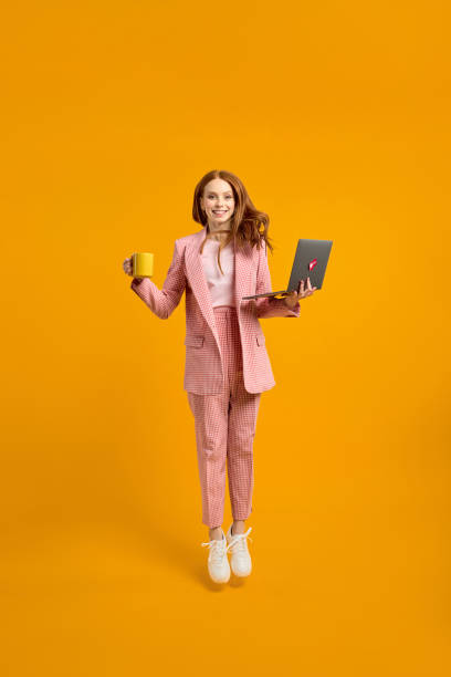 pełnometrażowe zdjęcie profilowe śmiesznej biznesowej damy, która skacze wysoko w górę, trzymając laptopa w rękach - vertical studio shot indoors pink zdjęcia i obrazy z banku zdjęć