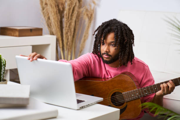 istock Man holding guitar take online lesson webcam on computer, music tutorial on laptop at home 1790804874