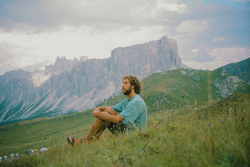 Serene man sitting on the meadow and enjoying Dolomites landscape