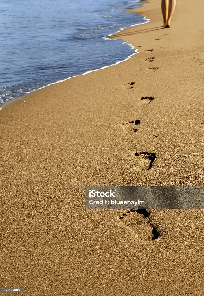 Beachwalk A young woman walks along the beach. Footprint Stock Photo