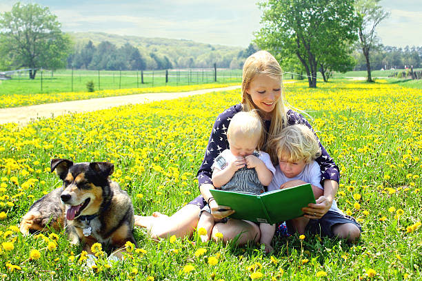 mutter liest buch für kinder im freien - baby toddler child flower stock-fotos und bilder