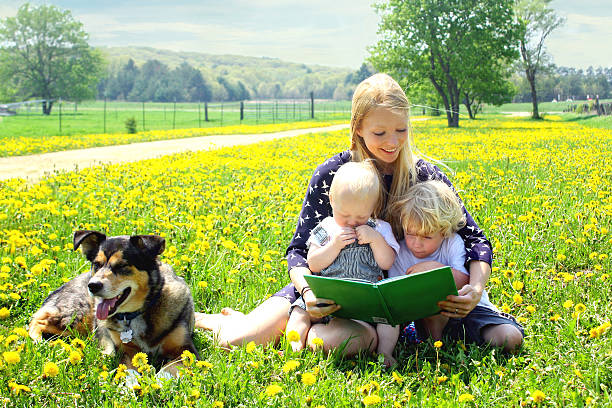 мать, чтение книги для детей за - baby spring child grass стоковые фото и изображения