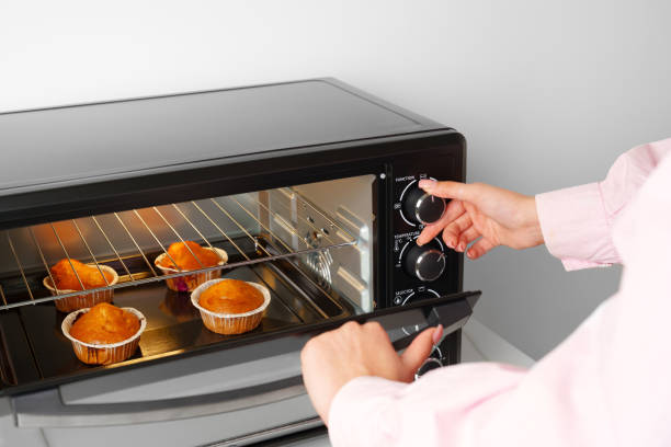 istock Woman's hands taking buscuit cupcakes out of mini oven 1790814242