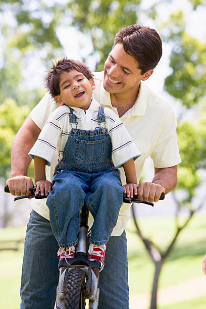 istock Man and young boy on a bike outdoors smiling 179083006