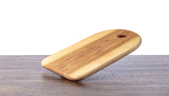 Cutting board falling on an old wooden table. Food preparation. Culinary background. Empty wooden cutting board, product display space.