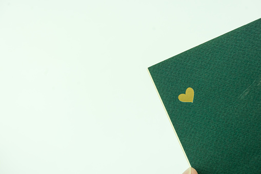 Golden alone heart on green paper notebook with copy space. Love and Happy Valentine day concept
