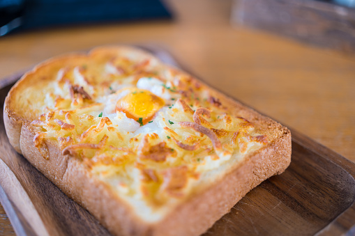 Egg in a hole and cheese toast serve on wooden board. Sandwiches for breakfast. The concept of delicious food, Selective focus.