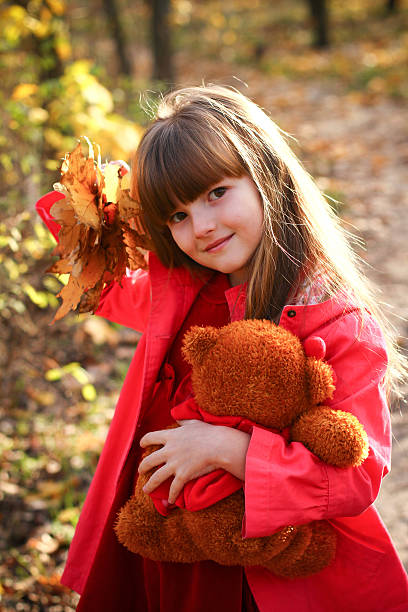 istock little girl with maple leaves and teddy bear 179086065