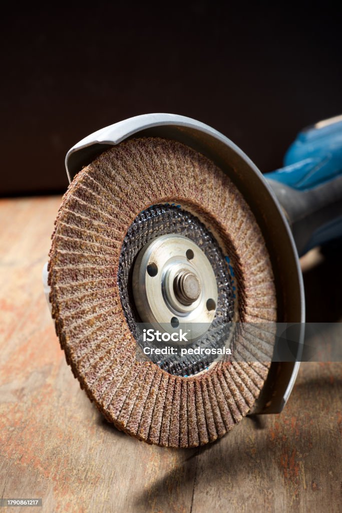 Close-up of a battery-powered electric angular grinder Close up of a professional grinding machine on a wooden board Blue Stock Photo