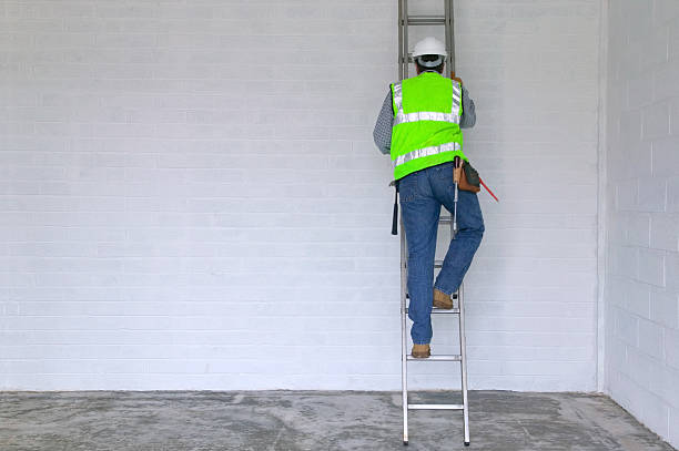 Workman climbing a ladder "Workman in reflective vest and hard hat climbing a ladder, slight motion blur on the man." ladder photos stock pictures, royalty-free photos & images