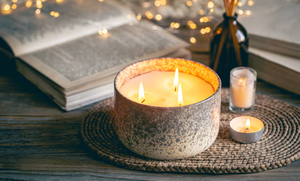 Cozy winter composition with candles on a blurred background with books.
