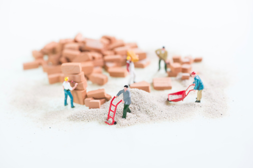 Miniature workmen doing construction brickwork