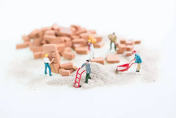 Miniature workmen doing construction brickwork