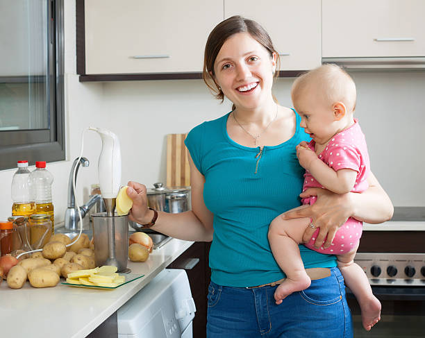 Happy woman with child together cooking mashed potatoes in kitchen at home