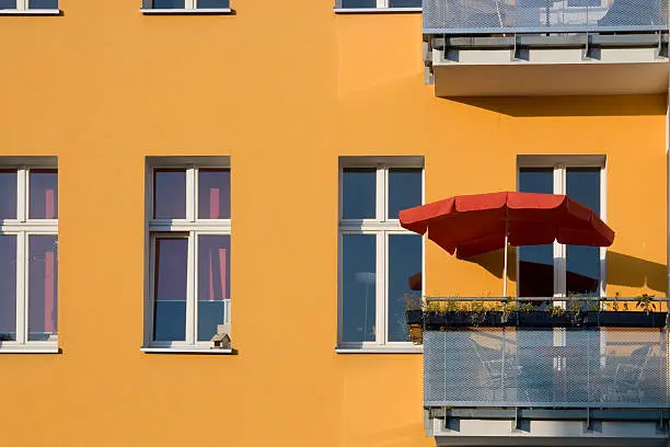 Orange housefront with a red umbrella in Berlin.