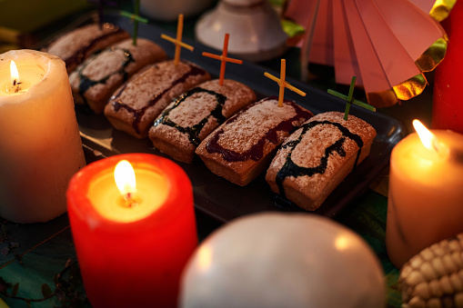 Close-up of homemade cakes cooked in the shape of graves decorating with crosses with candles on the table